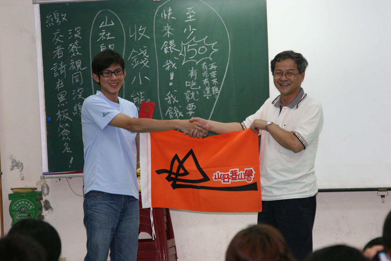 晚會開始, 先由理事長致贈薄禮 -- 紅包一只.  後方黑板的字, 令人不禁莞爾!
